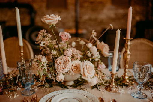 Wedding reception table setting with china, blue goblets, candles and florals