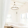 Partial view of white sectional, curved. Natural light coming through windows behind. Hanging circular light.