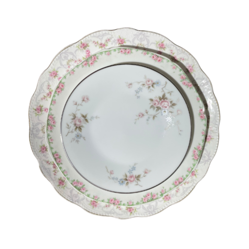 Set of 3 vintage china plates in 3 different sizes stacked on top of each other. Mismatched pink patterns on white background