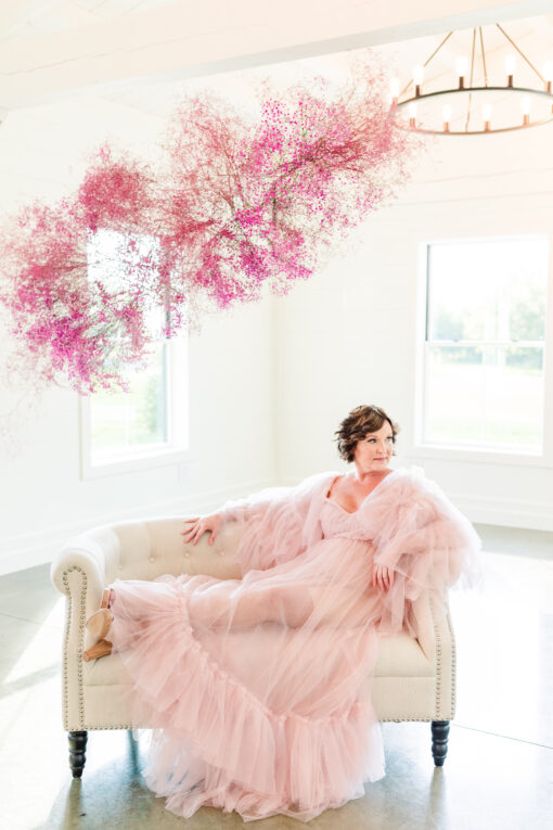 White round settee with a woman in a pink dress sitting with her legs up