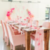 Pink seats velvet seats and pink tablesetting on a farm table with white walls behind