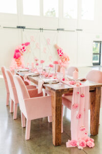 Pink seats velvet seats and pink tablesetting on a farm table with white walls behind