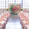 Pink arm chairs used in wedding ceremony. Windows and brick wall in the background.
