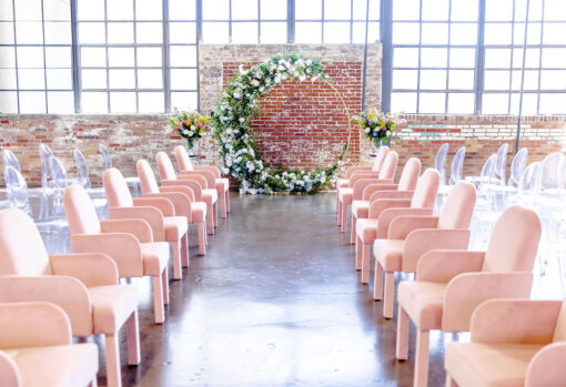 Pink arm chairs used in wedding ceremony. Windows and brick wall in the background.