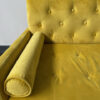 Close up of arm pillow and back of yellow sofa.