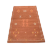 Rust colored rug with geometric diamond shaped designs in white, yellow and orange.