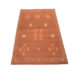 Rust colored rug with geometric diamond shaped designs in white, yellow and orange.