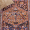 4x6 foot rug with floral patterns around boarder and design in the center. Hues of red with blue, cream and other neutral hues. Close up