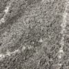 Close up of the high gray pile and thin white lines of this shag rug.