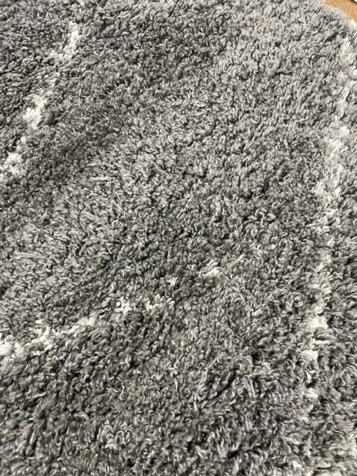 Close up of the high gray pile and thin white lines of this shag rug.