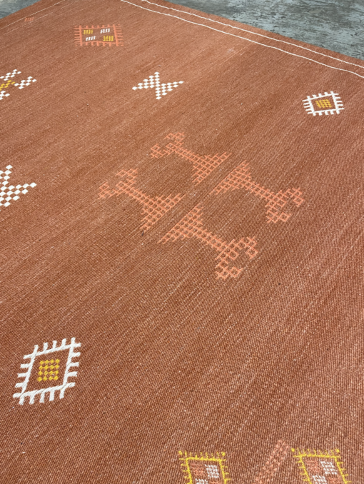 Rust colored rug with orange and white geometric designs