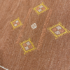 Close up of rug details with 4 yellow diamonds and smaller white and orange diamonds inside, creating a larger diamond.