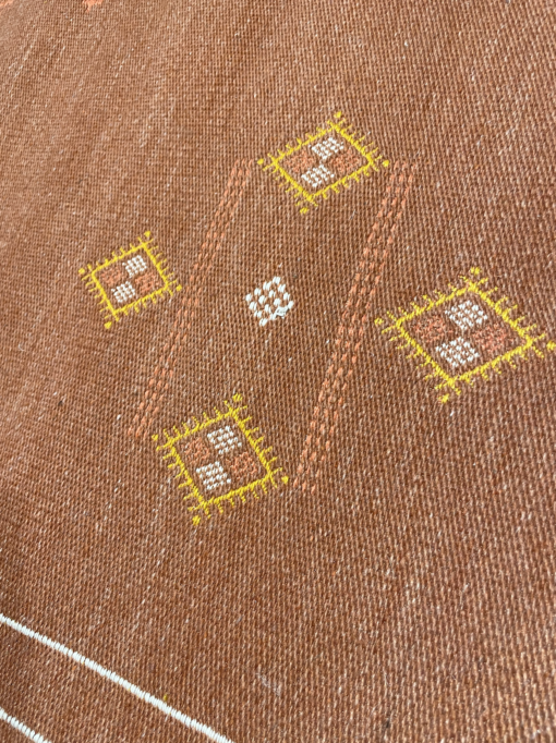 Close up of rug details with 4 yellow diamonds and smaller white and orange diamonds inside, creating a larger diamond.