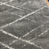 View of the gray rug with white lines making geometric overlapping diamonds.